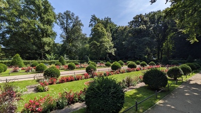 Flowers and bushes are neatly aligned in columns to establish a garden where people and can walk between those columns