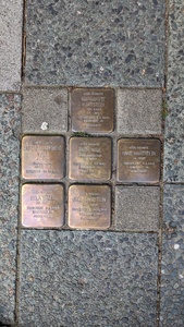 Between floor tiles a grid of brass plates can be found commemorating victims of the Holocaust