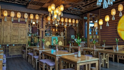 A room with wooden walls and desks and chairs is shown and lanterns are mounted on the ceiling