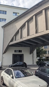 A house is visible and a huge metal container enters on the first floor where the container covers the train passage