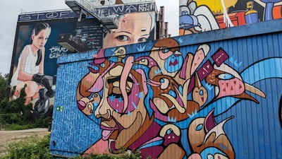 The graffiti on building sides show a colorful female head as well as a woman in boxing gear