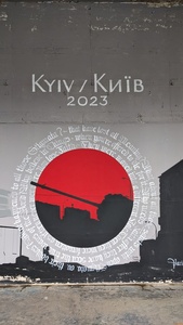 A graffiti with a black tank in front of red color inside a circle and text is wrapped around the circle