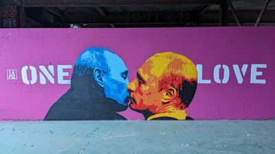 Two heads of Vladimir Putin are kissing each other are shown