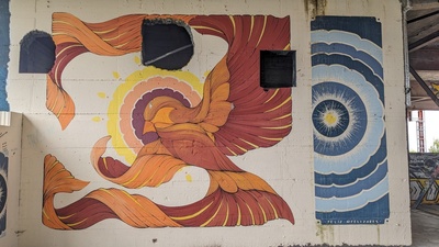 A graffiti in red and blue colors is shown and a large bird with long feathers is drawn in red