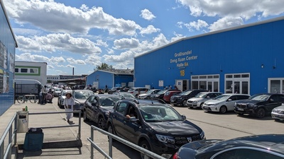 Blue large market halls are shown next to each other with cars in front