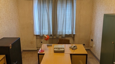 A room with several cupboards and a wooden desk is shown