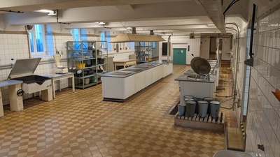 A kitchen with old-style equipment and many tabletops is shown