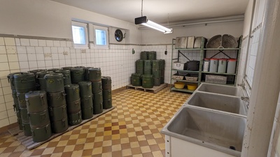 On the left many green metal containers are stacked and the left shows sinks for cooking activities