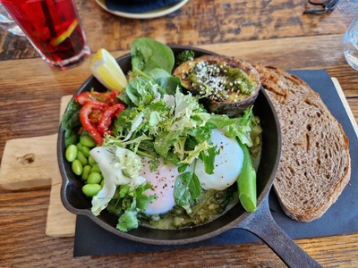 A pan and bread is visible and the pan is filled with vegetables like salad and beans